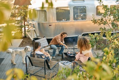 Family sitting outside accommodations with dog, cooking food