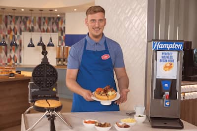 Waffle boss Chris holds a plate with waffle on it