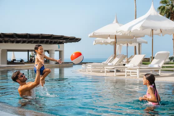 family playing in outdoor pool