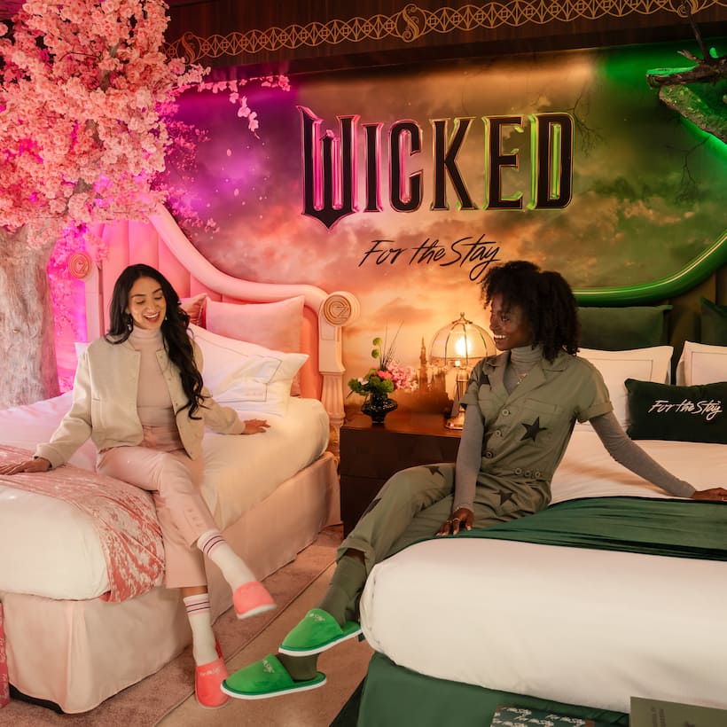 Two women lounge and laugh in the enchanting two bedroom suite inspired by the film Wicked.