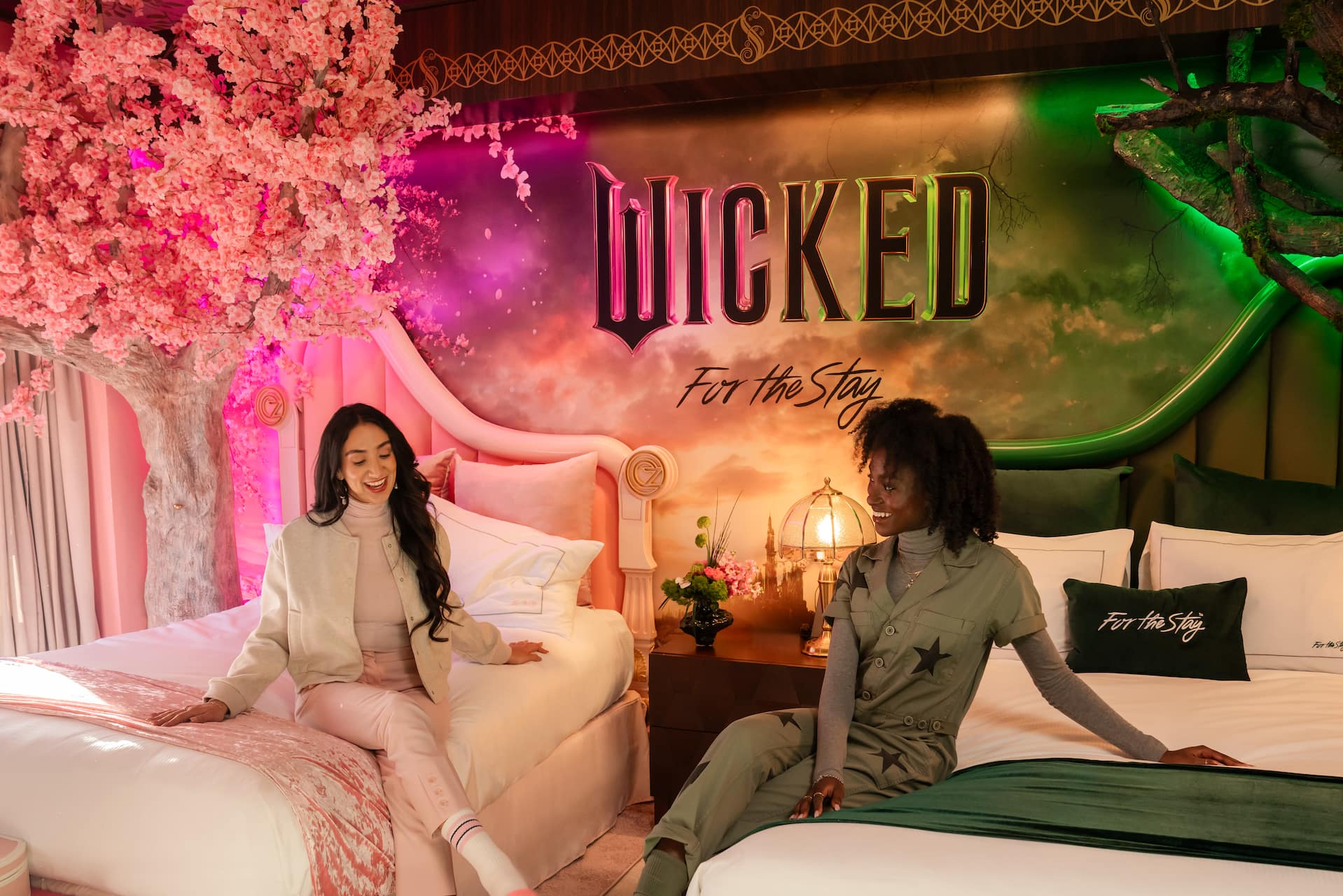 Two women lounge and laugh in the enchanting two bedroom suite inspired by the film Wicked.
